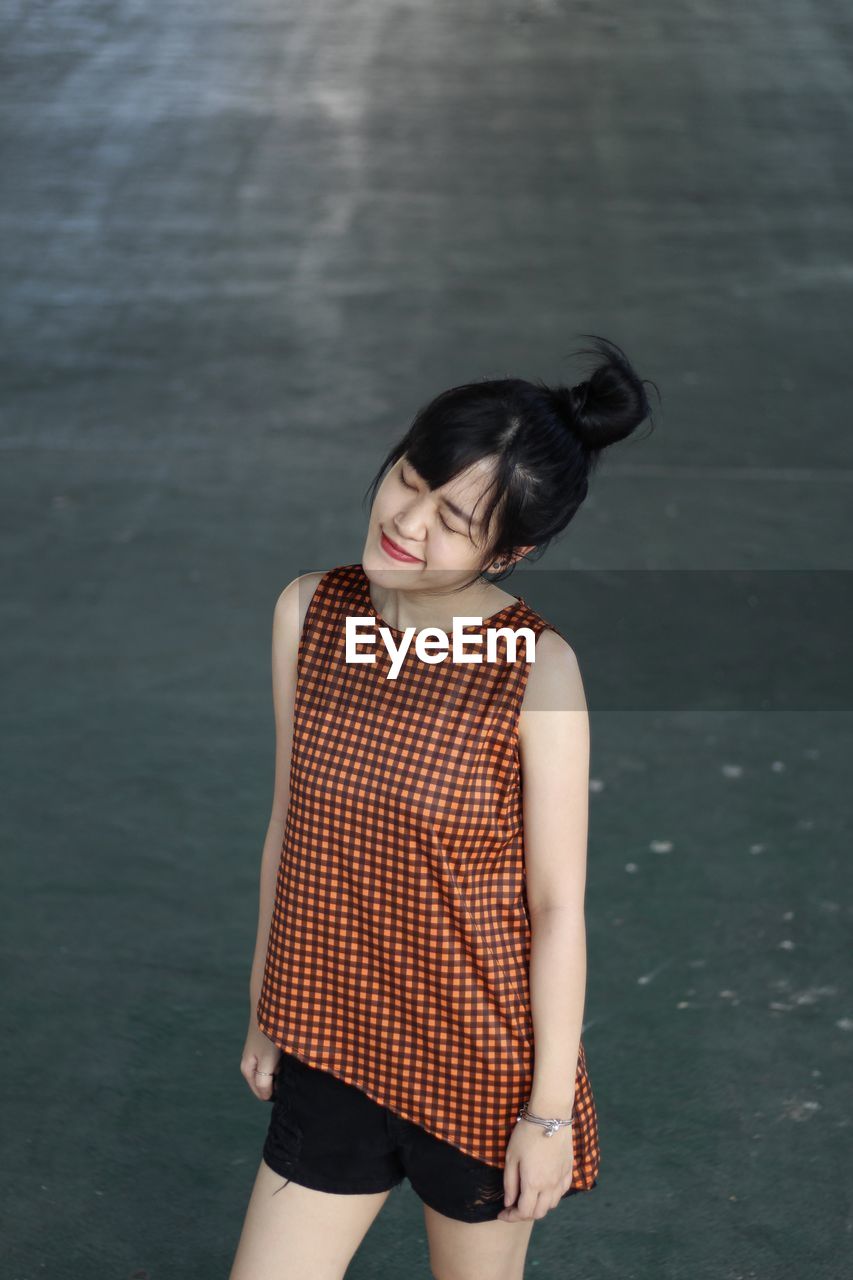 High angle view of young woman with eyes closed standing on road