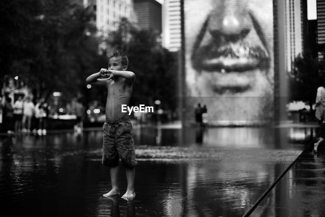 REAR VIEW OF SHIRTLESS BOY WITH SWIMMING POOL