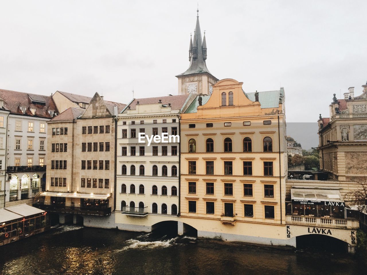 Buildings by river in city against sky