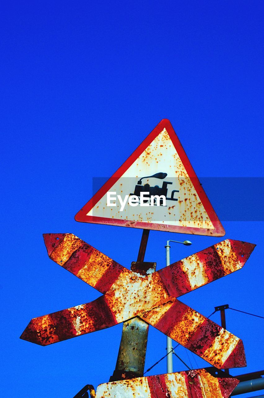 Low angle view of warning triangle against clear blue sky