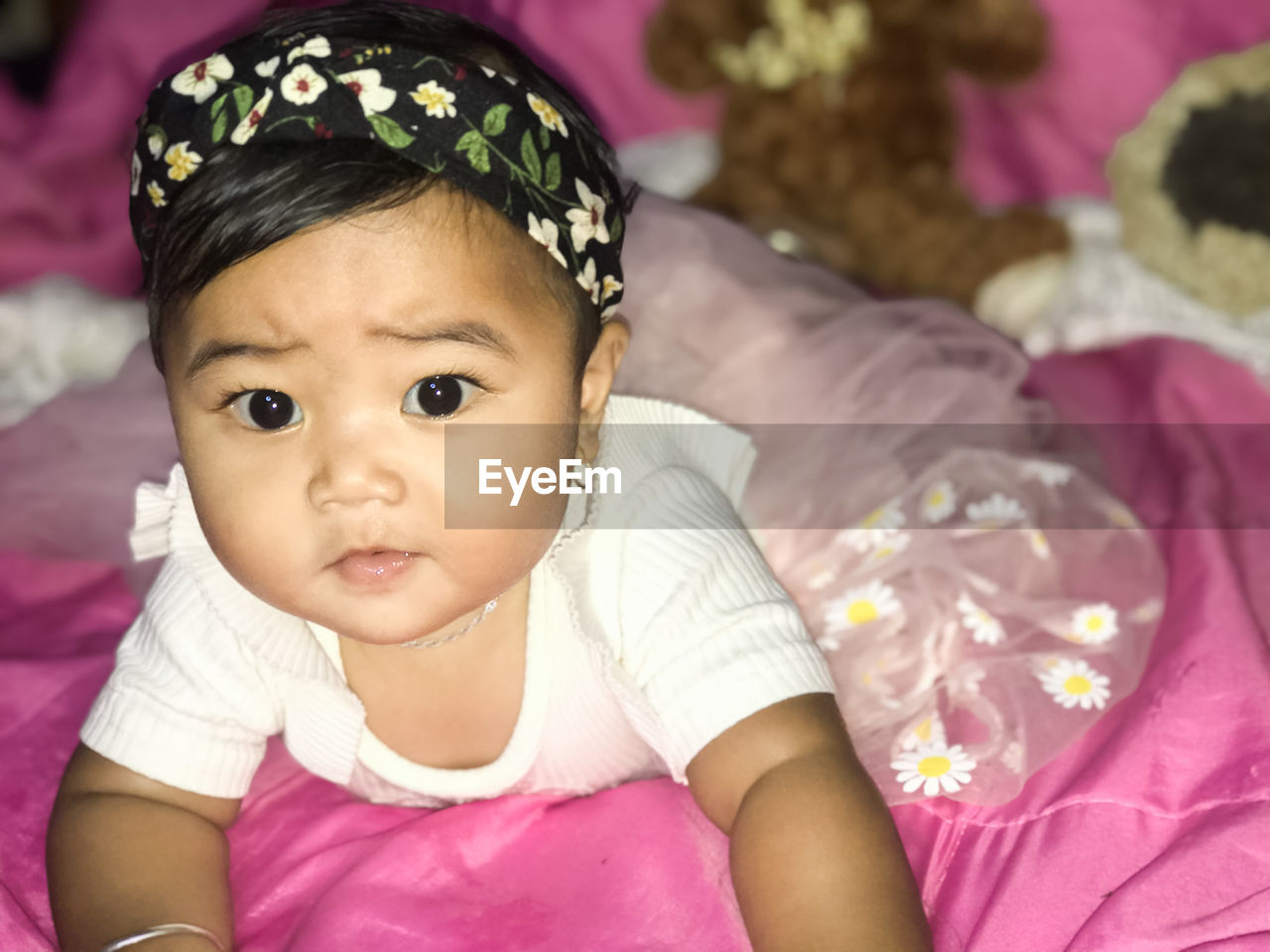 Portrait of cute baby girl on bed at home