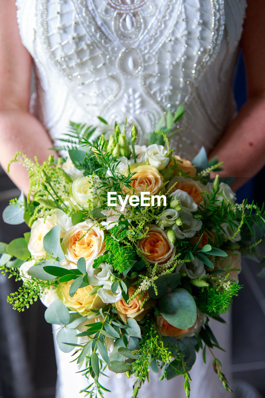 Midsection of bride holding bouquet