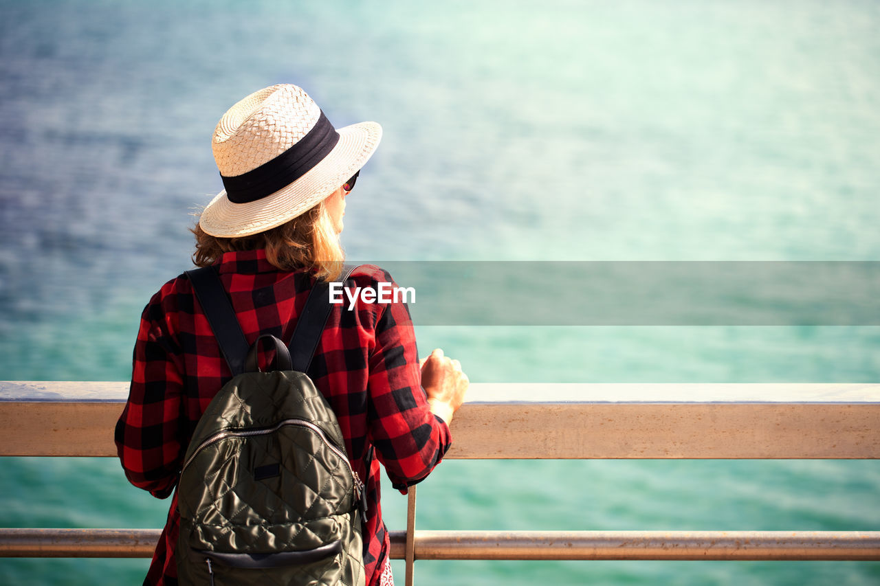 REAR VIEW OF WOMAN LOOKING AT SEA