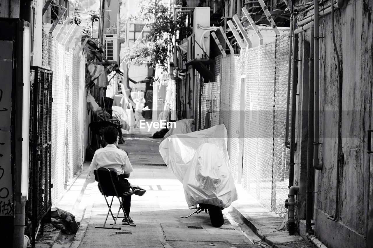 Man sitting on sidewalk in city