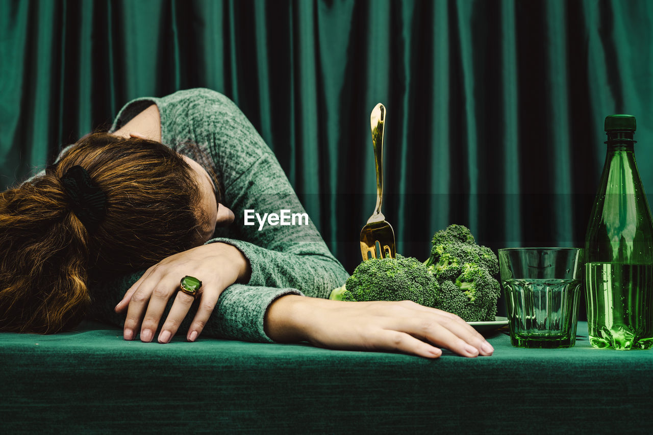 Mid adult woman lying with head down on table