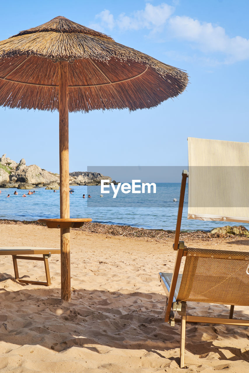 DECK CHAIRS ON BEACH AGAINST SKY