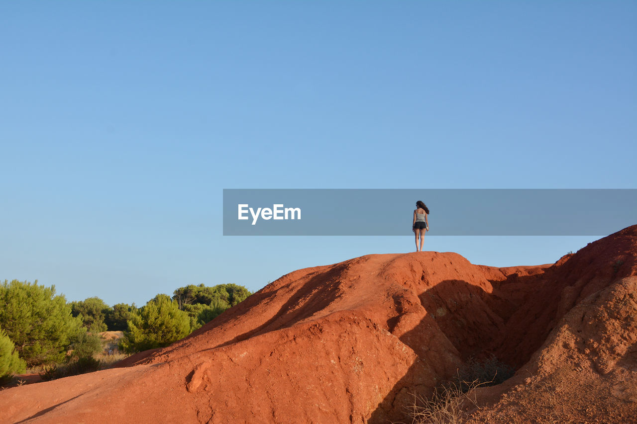 MAN STANDING ON ROCK AGAINST SKY