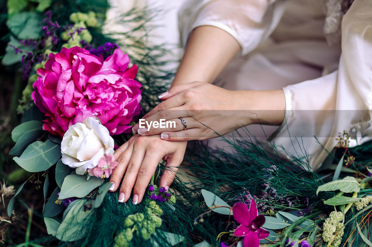 Midsection of young woman sitting by bouquet