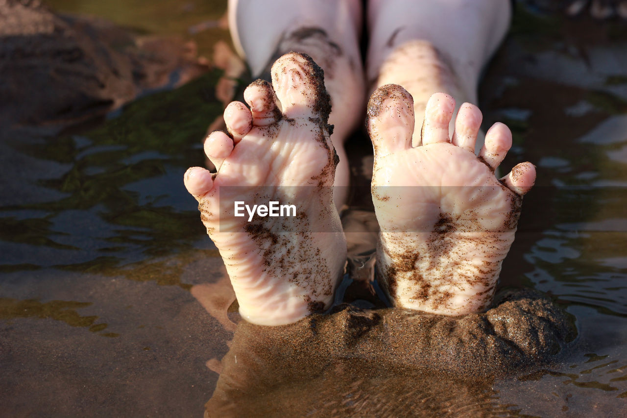 Bare feet of a child on a river in the sand