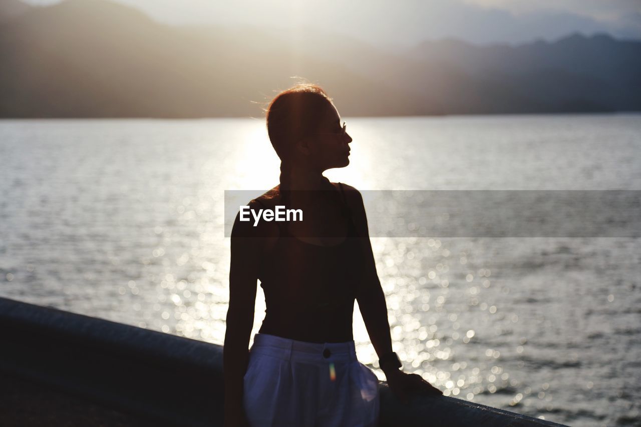 Woman standing against sea during sunset