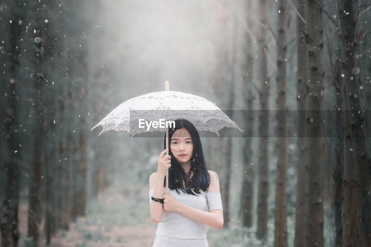 Portrait of beautiful young woman holding umbrella during winter