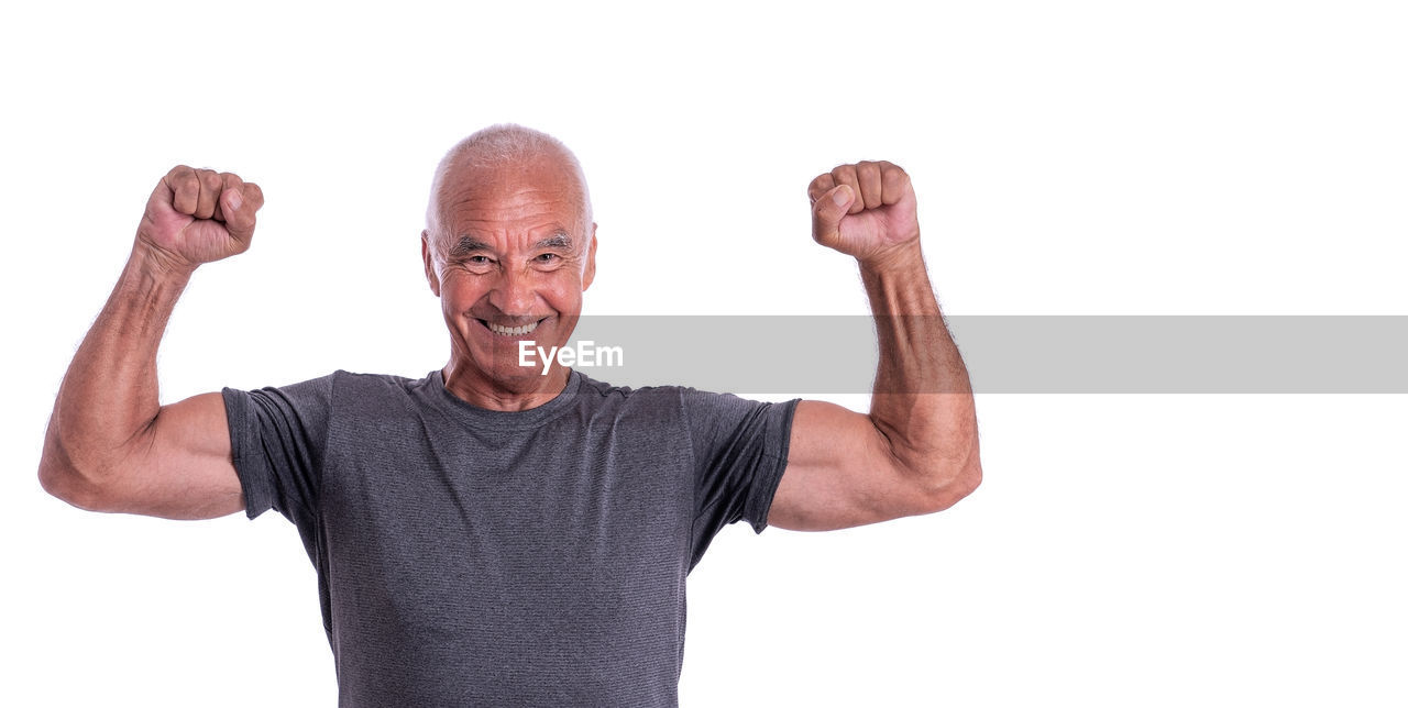 PORTRAIT OF SMILING MAN STANDING AGAINST GRAY BACKGROUND