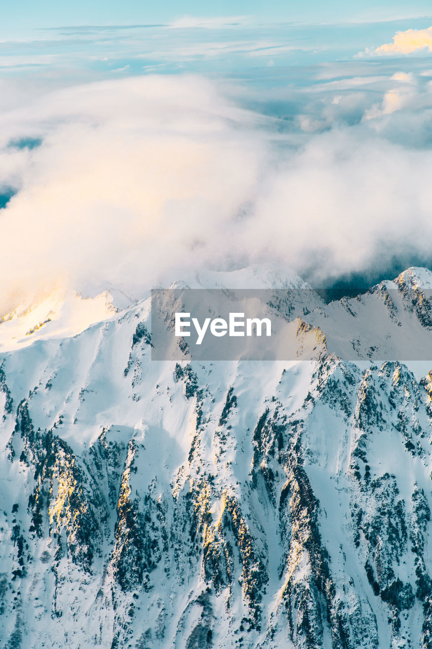 Aerial view of snowcapped mountains by sea against sky