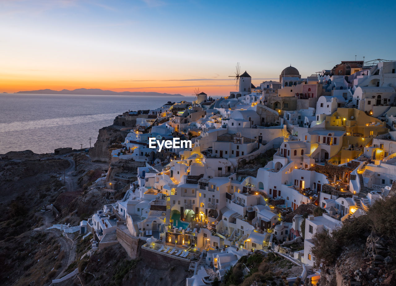 High angle view of townscape by sea against sky during sunset