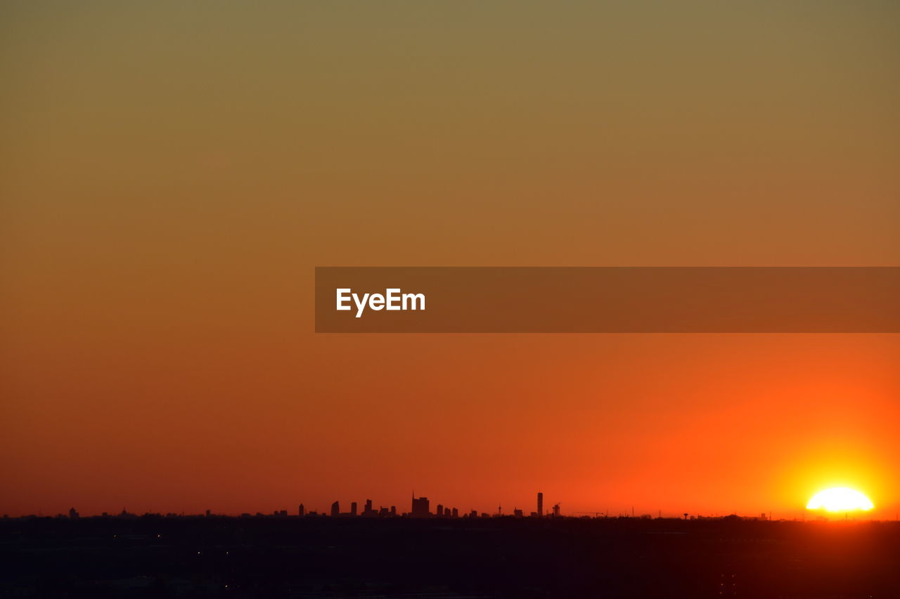 Silhouette landscape against orange sky during sunset