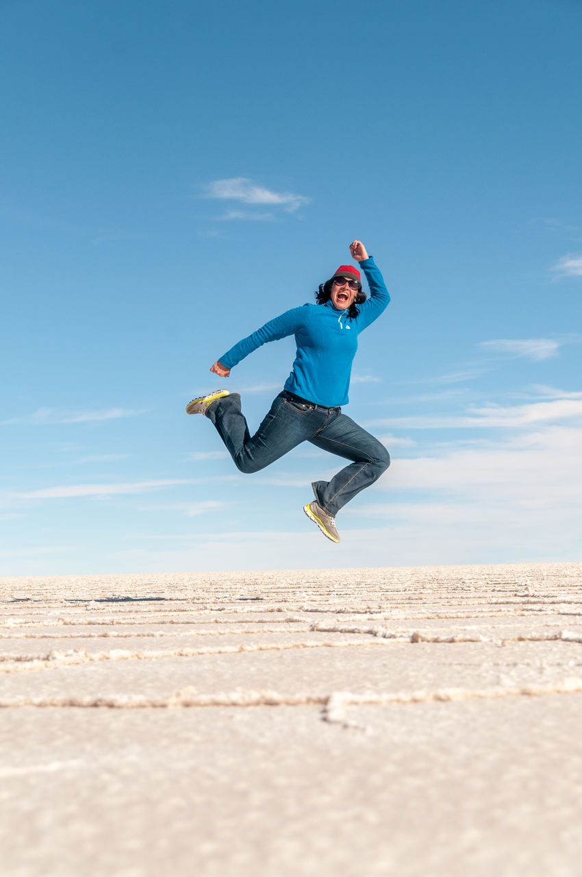 LOW ANGLE VIEW OF MAN JUMPING IN MID-AIR