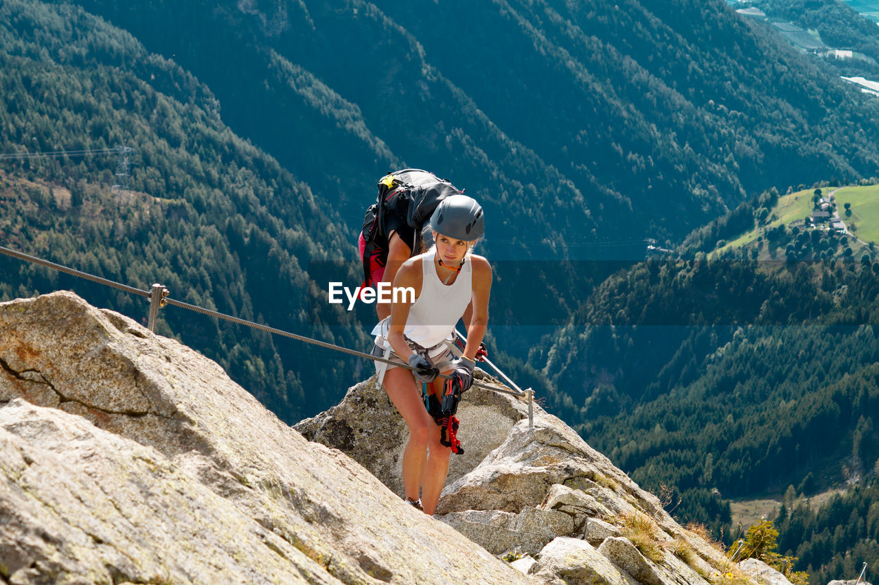 Full length of woman climbing rocks in a mountain at heini-holzer-klettersteig, meran 2000