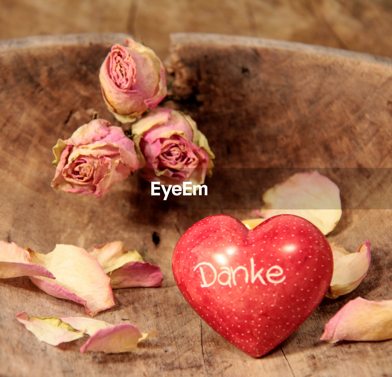 Close-up of heart shape with pink roses on wooden table