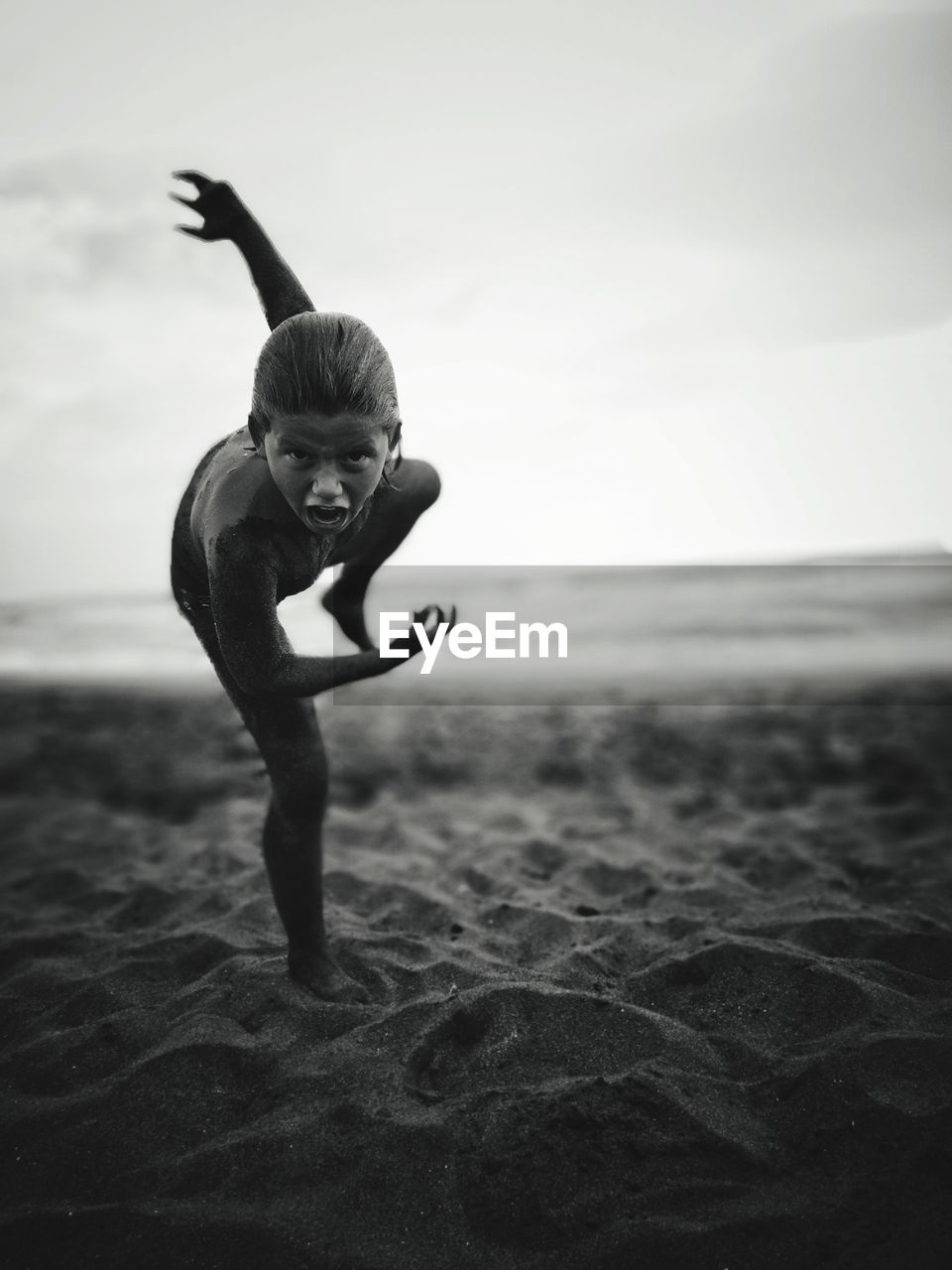 Portrait of shirtless boy screaming while playing at beach against sky