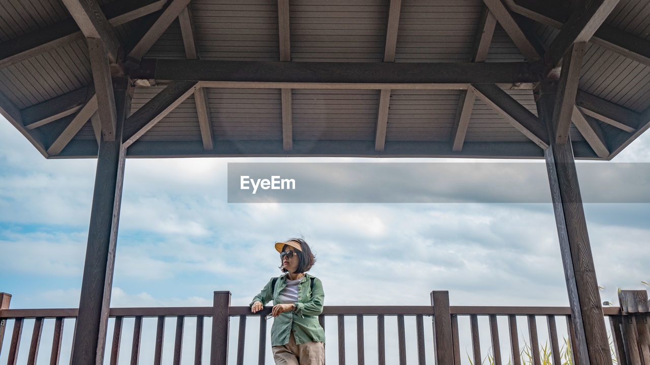 Rear view of woman standing on beach against sky