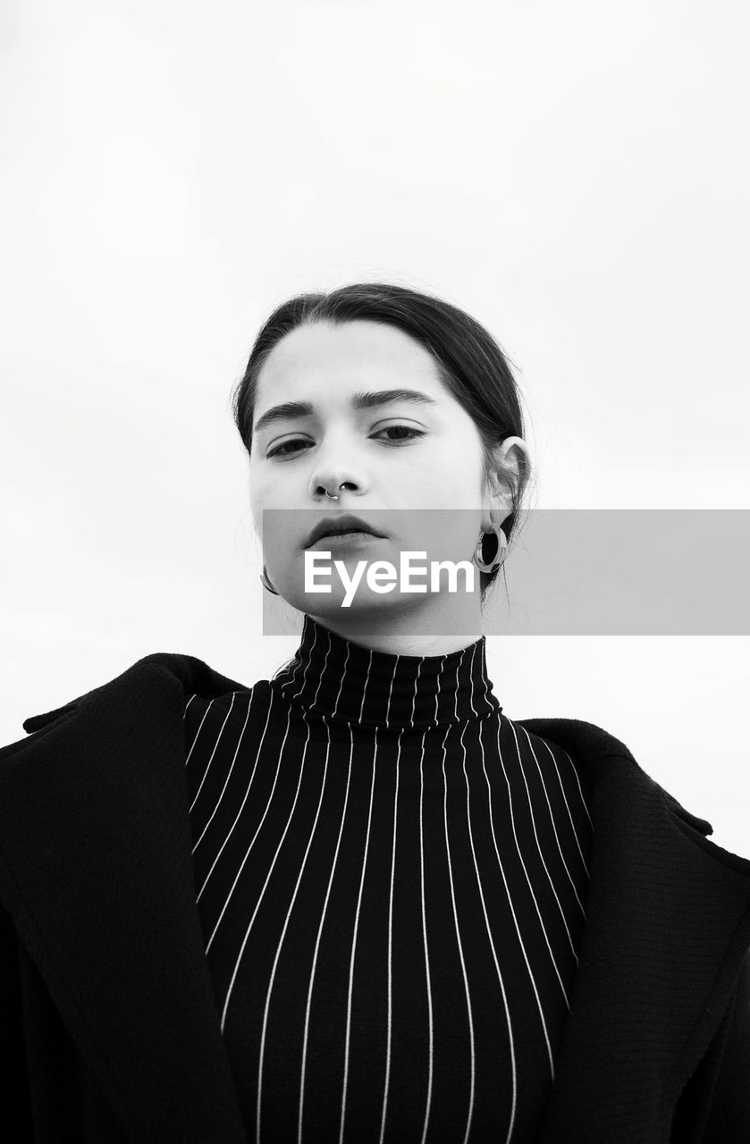 Portrait of young woman against clear sky