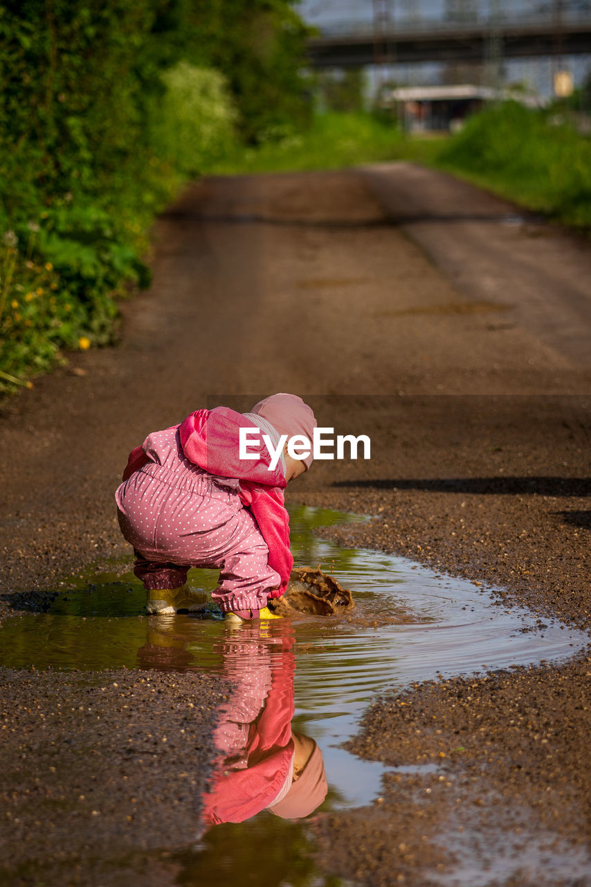 A small child is playing in a rain puddle