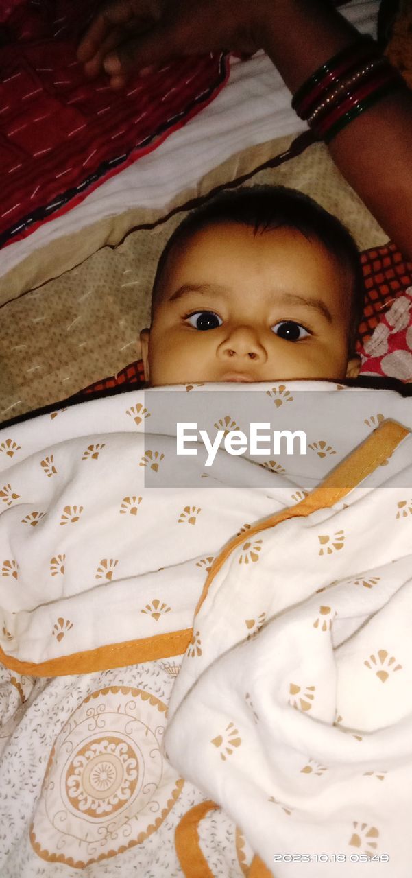 child, childhood, one person, lying down, bed, portrait, indoors, furniture, person, skin, looking at camera, relaxation, high angle view, baby, cute, innocence, bedroom, toddler, lifestyles, lying on back, men, emotion, headshot, front view, blanket, human face, clothing, female, domestic room, pillow, linen