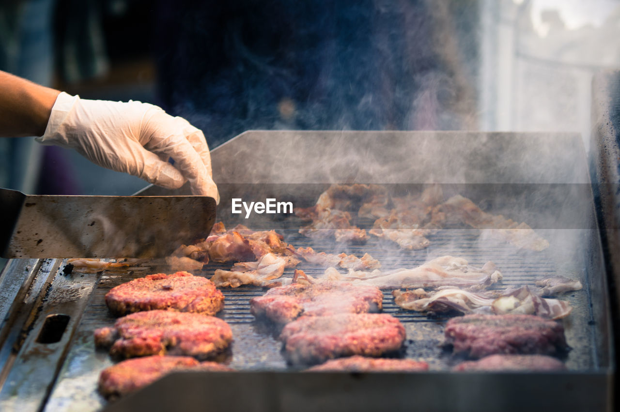 Close-up of person preparing food on barbecue grill