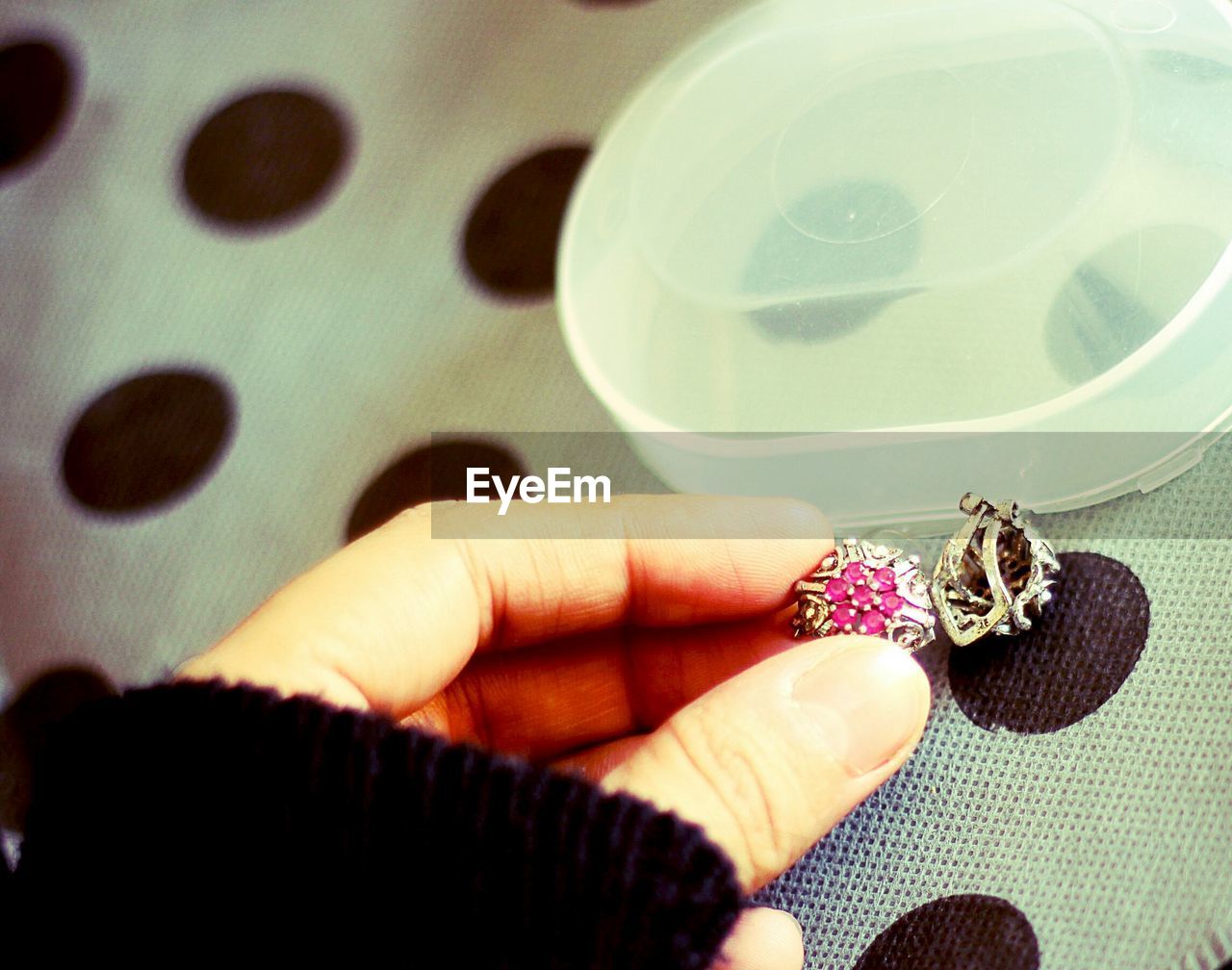 Cropped hand of woman holding ring at table