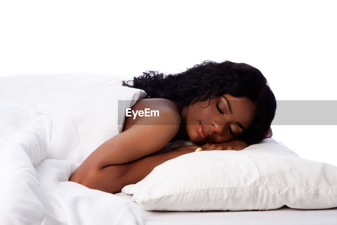Young woman sleeping on bed against white background