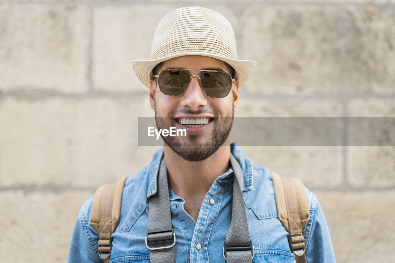 Portrait of young man wearing hat against wall