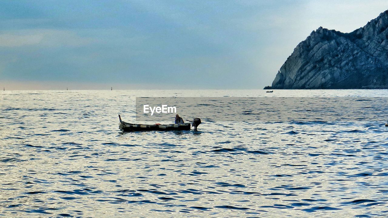 Man in motorboat sailing over sea against sky