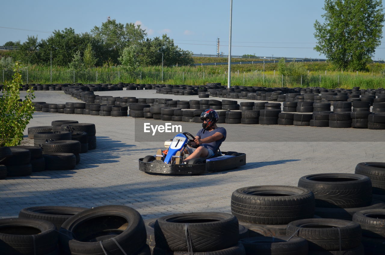 Man driving go-cart amidst tires on street