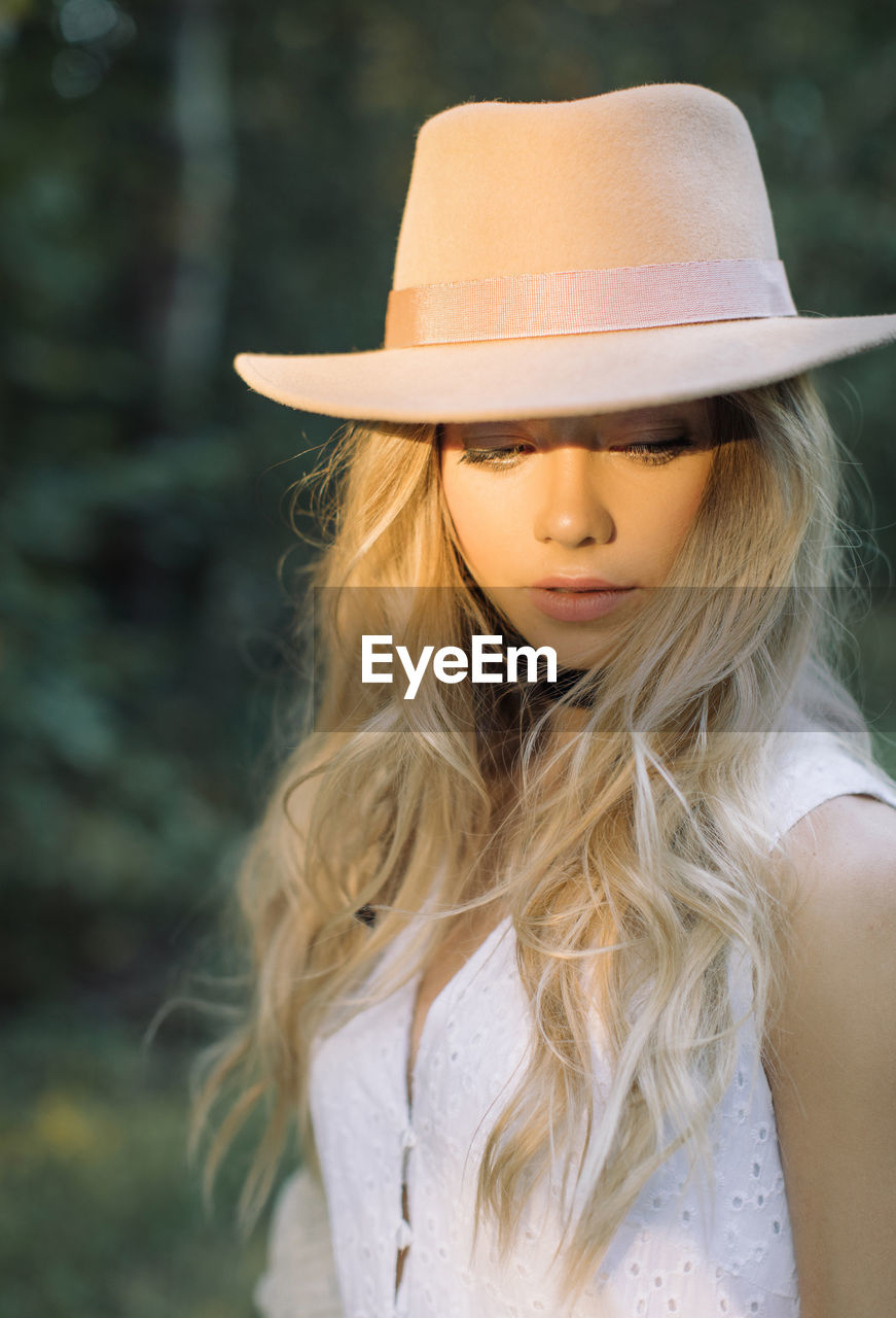 Woman wearing hat looking away at forest