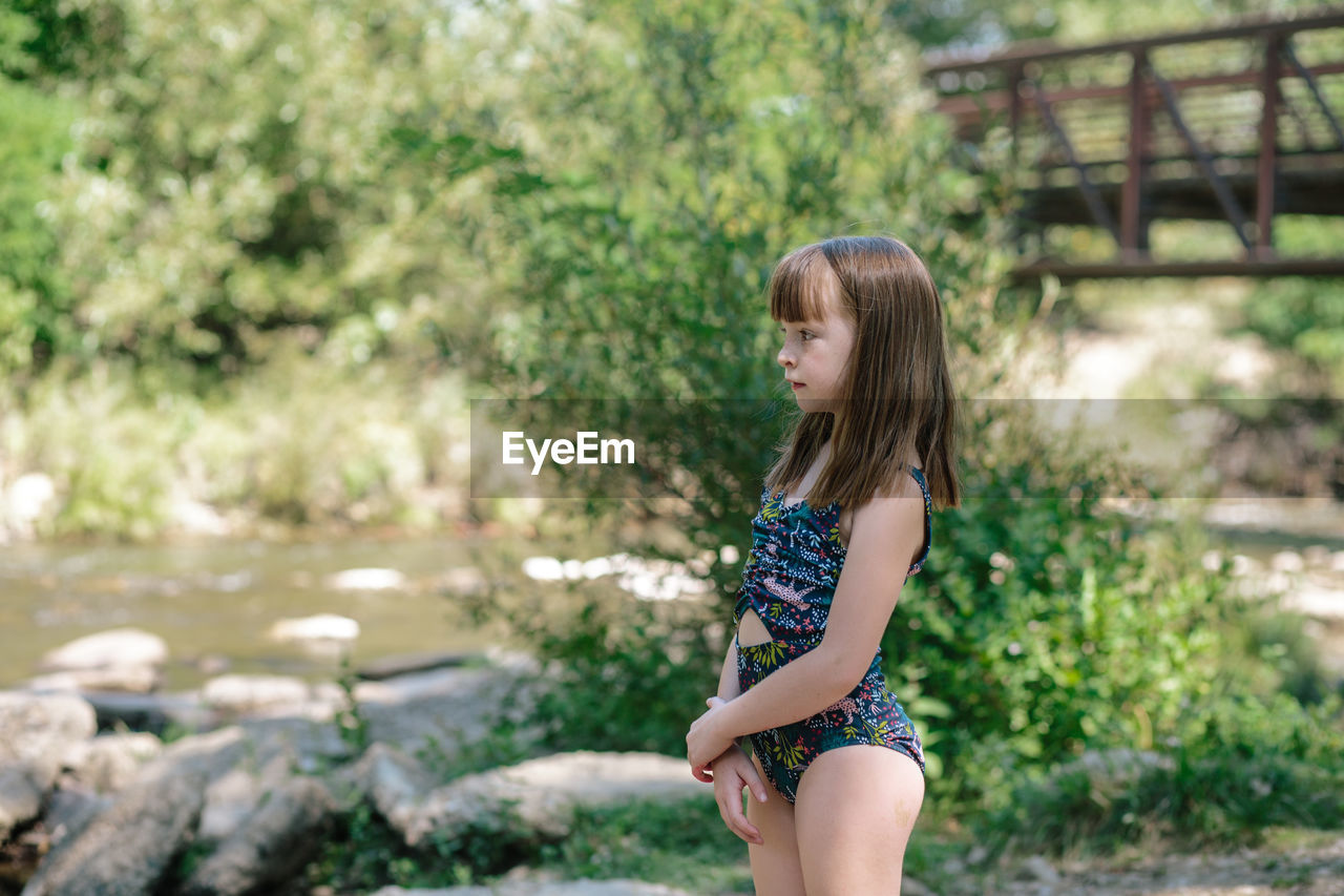 Young girl standing next to a stream on a sunny summer day