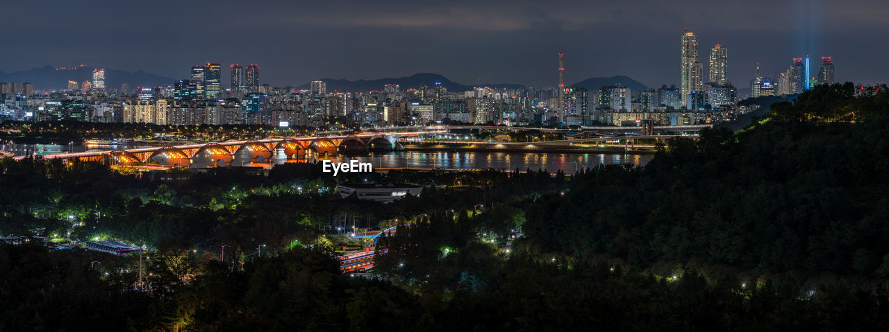 ILLUMINATED CITY BY RIVER AGAINST SKY