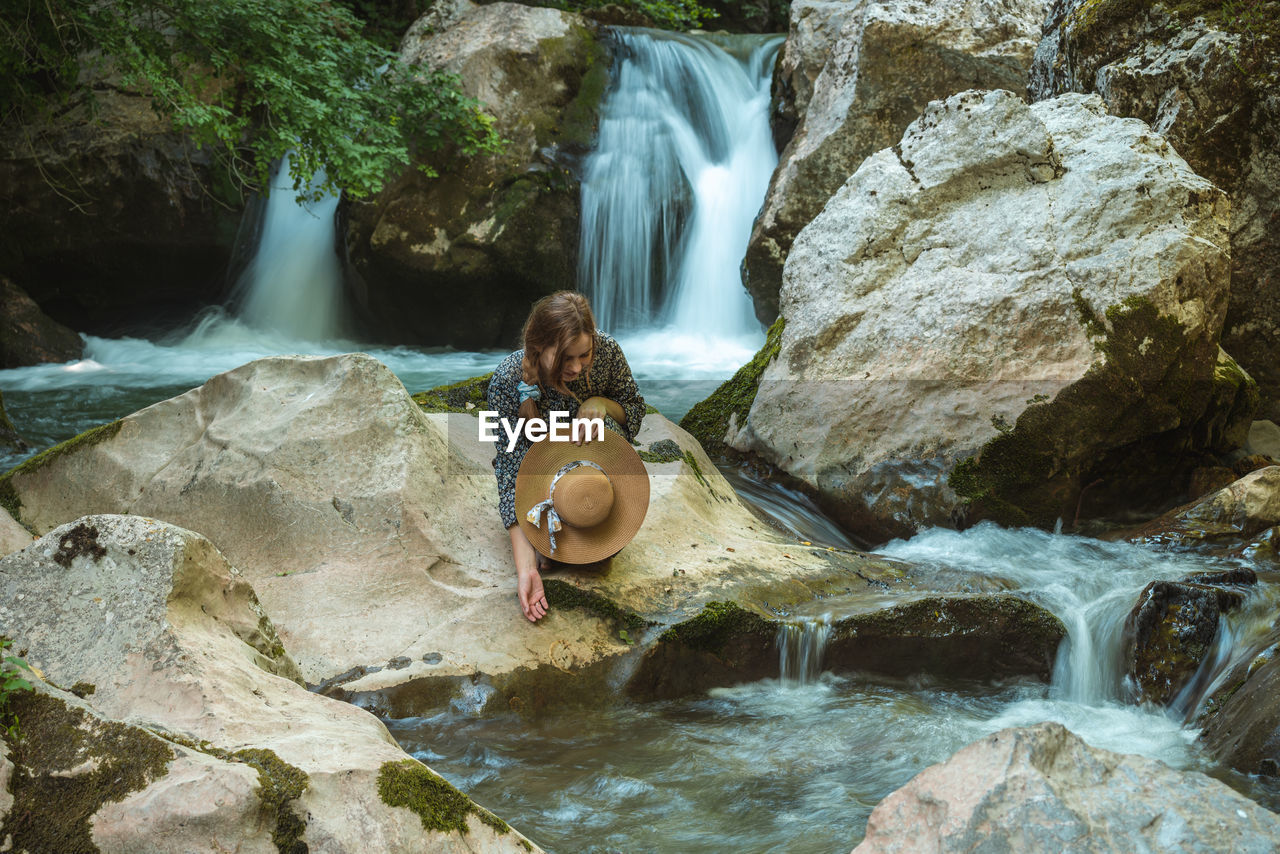 Young woman with hat enjoying natural water spring and slops