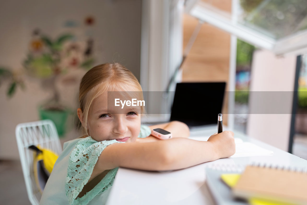 Portrait of a girl sitting on table at home