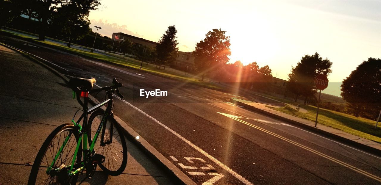 BICYCLE ON ROAD AGAINST SKY AT SUNSET