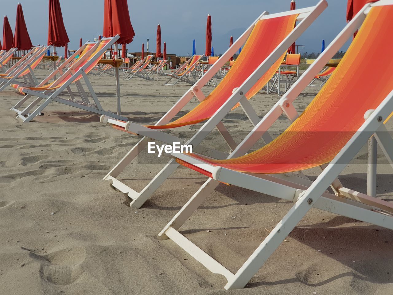 Empty chairs on beach against sea