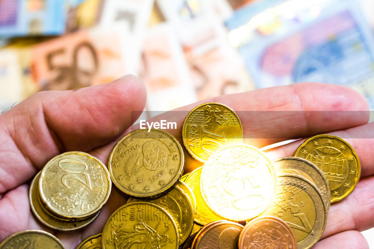 CLOSE-UP OF HAND HOLDING COINS WITH TATTOO ON BACKGROUND