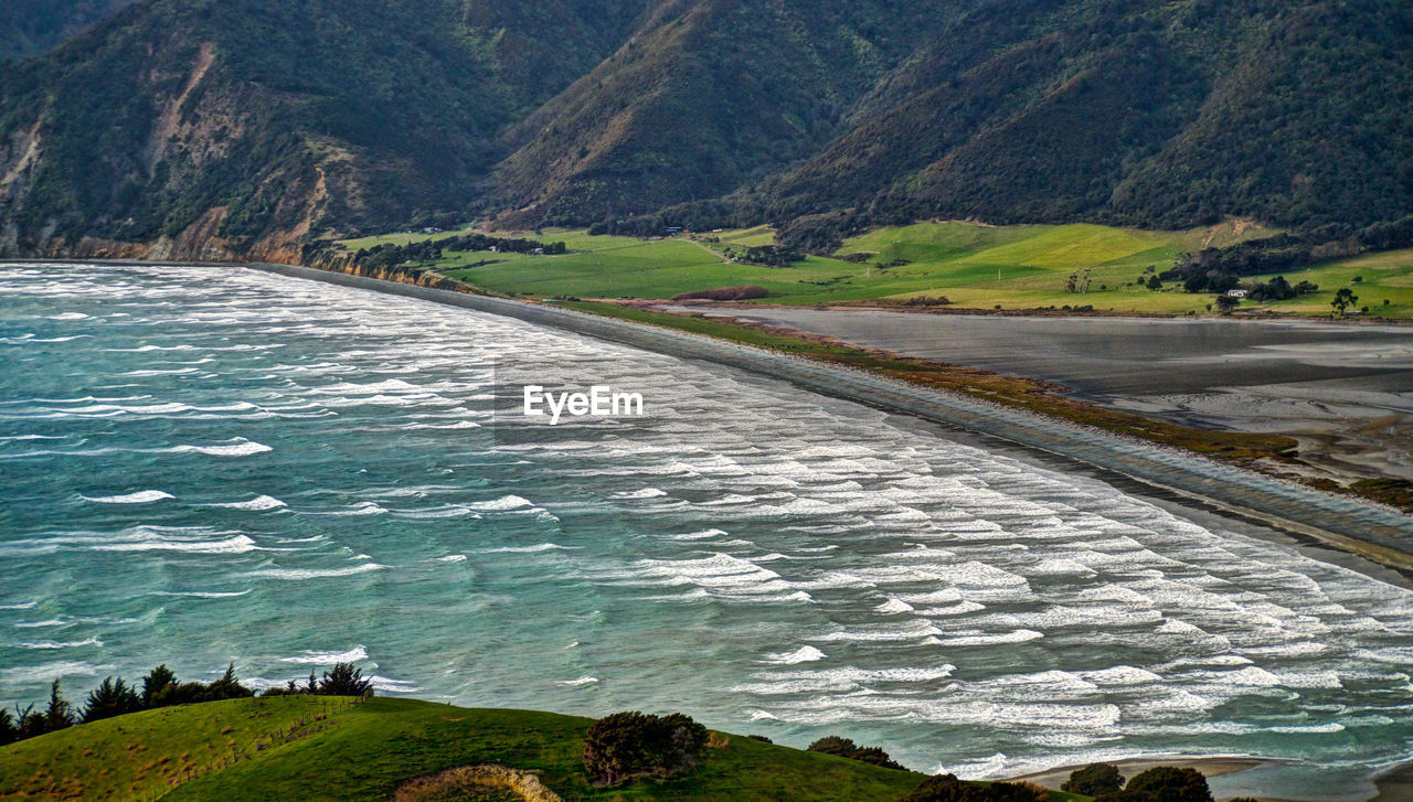 Scenic view of river by mountains against sky