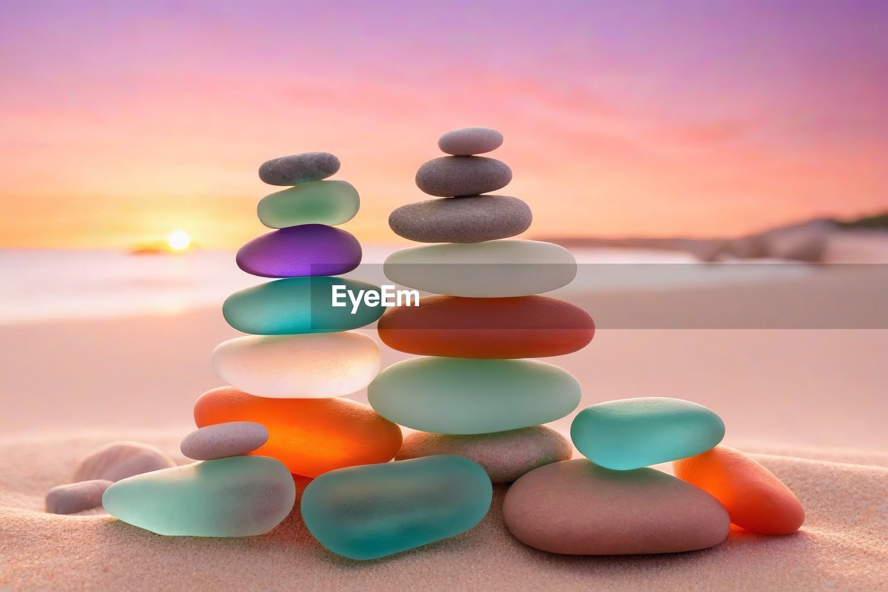 multi colored, land, nature, sunset, sky, no people, blue, beach, large group of objects, orange color, sand, water, zen-like, tranquility, environment, rock, balance, outdoors, focus on foreground, vibrant color, tranquil scene, sea