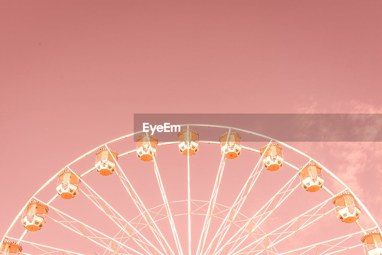 Low angle view of ferris wheel against pink sky