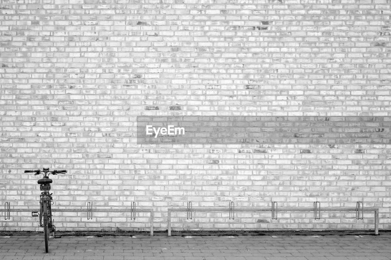 Bicycle parked against brick wall