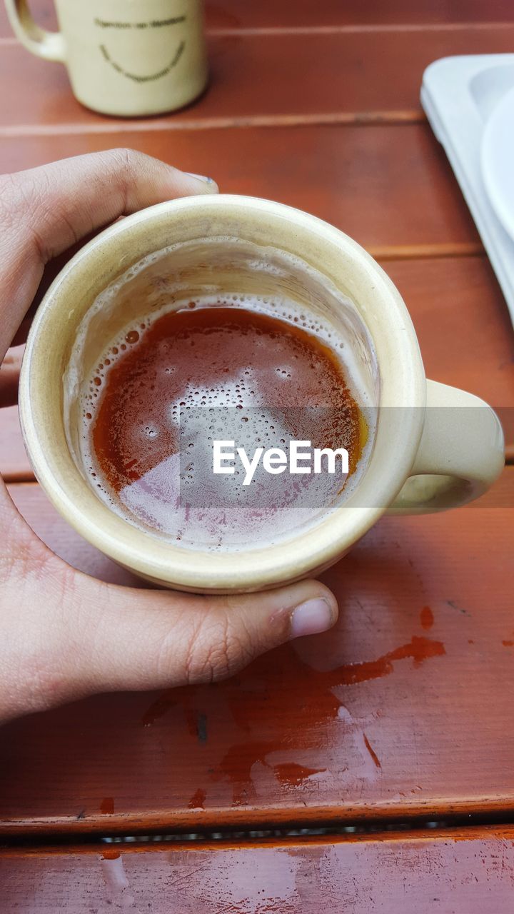 Cropped hand holding coffee cup at table