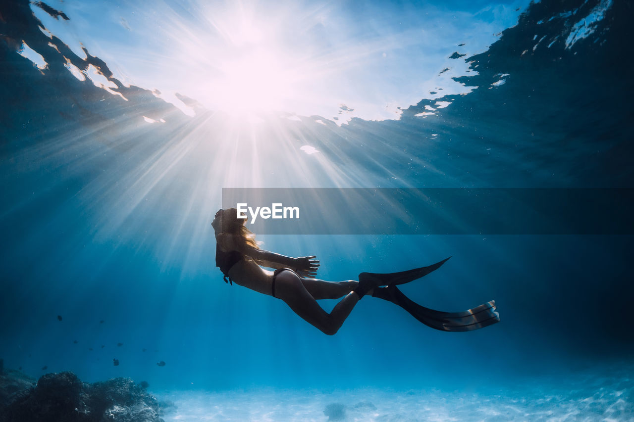 rear view of woman swimming in sea against sky