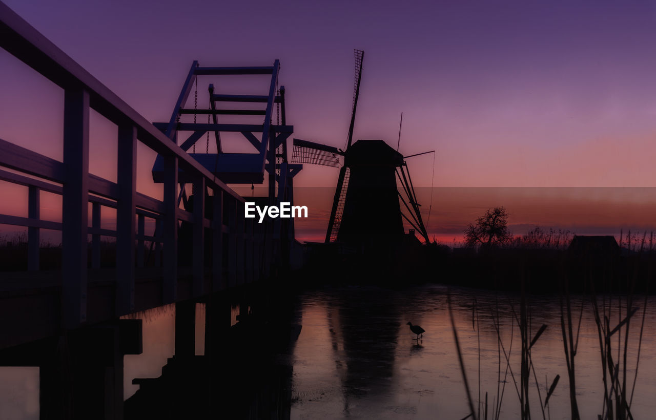 Traditional windmill on field during sunset