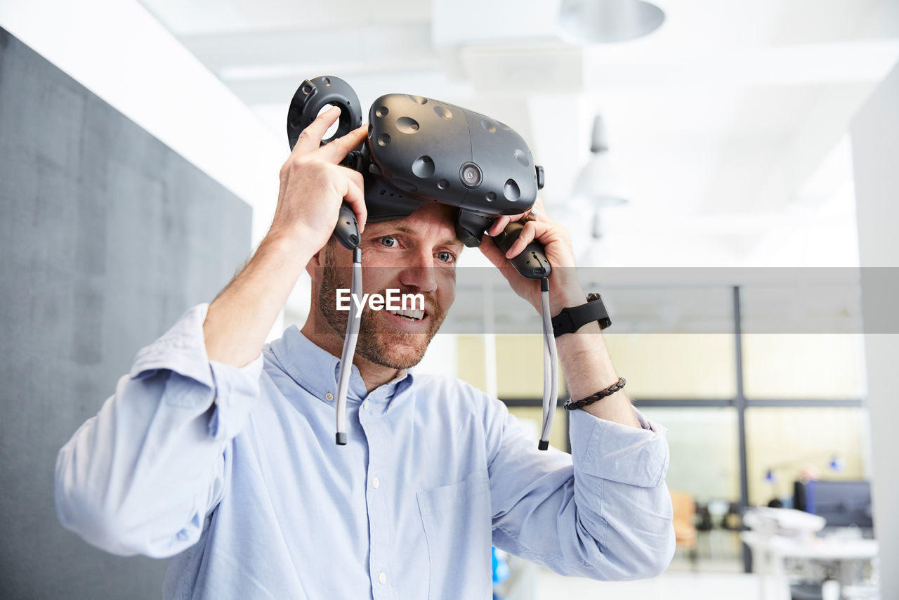 Smiling businessman wearing virtual reality stimulator at creative office