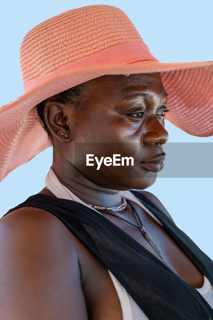 African woman sitting in the sun with summer hat on a beach